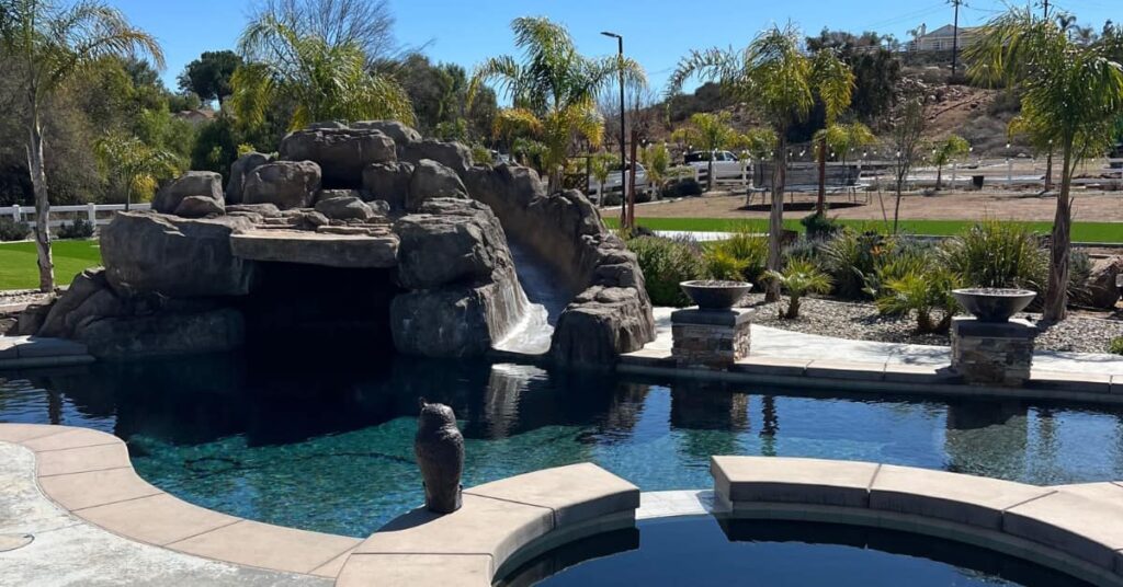 Natural rock pool grotto, waterfall, slide showing hot tub and landscap in distance