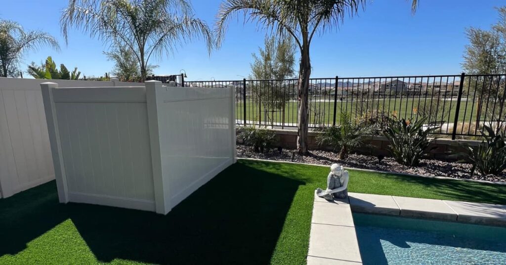 vinyl fence, green turf, fence and palm trees
