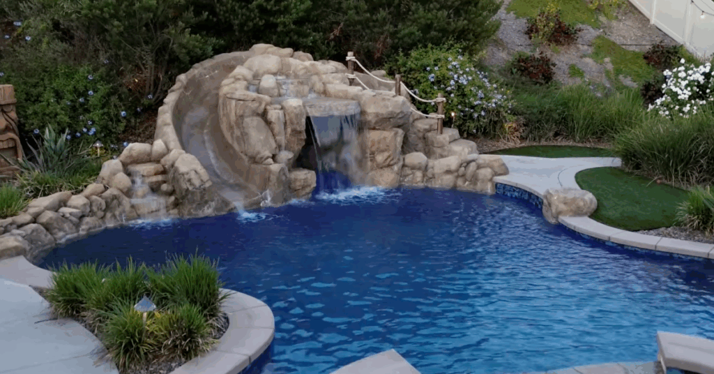 Luxury pool construction in Southern California featuring rock waterfall, grotto cave, and built-in slide with LED lights.