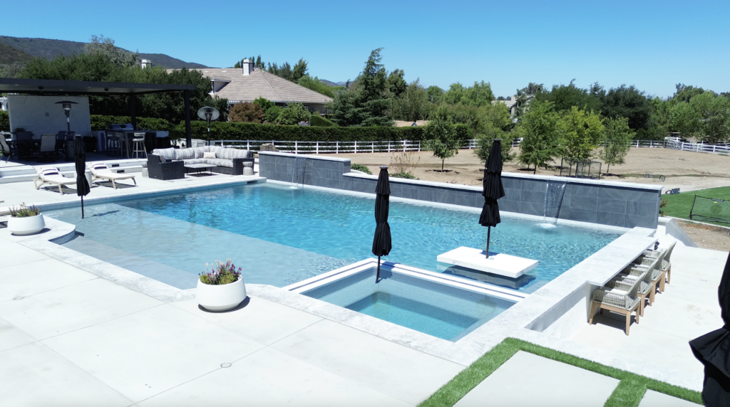 Modern pool with sun shelf, spa, and water features