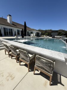 Luxury backyard pool with swim-up seating and shaded patio.