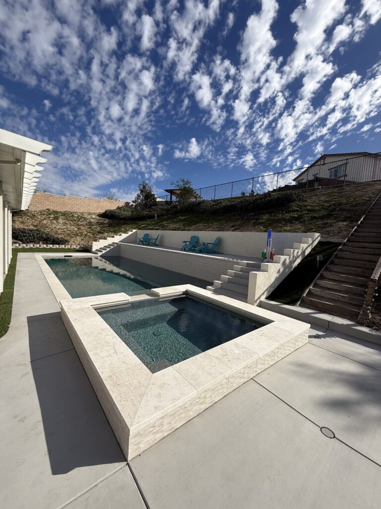 Modern backyard pool and spa with terraced seating