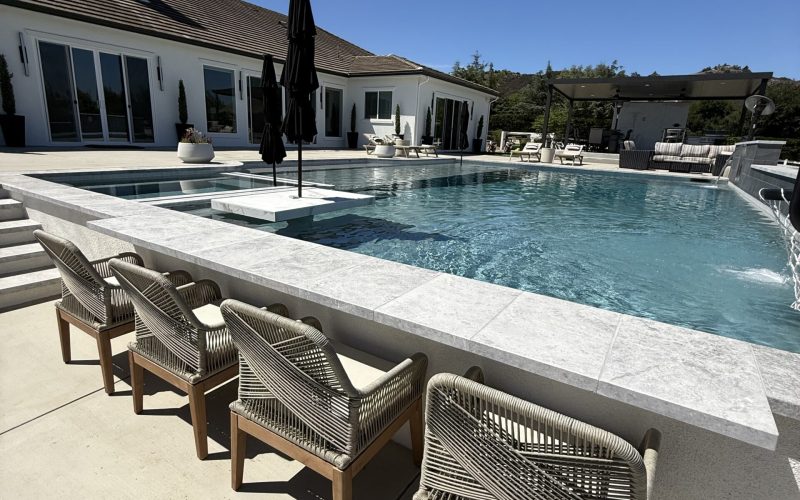 Luxury backyard pool with swim-up seating and shaded patio.