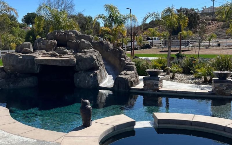 Natural rock pool grotto, waterfall, slide showing hot tub and landscap in distance